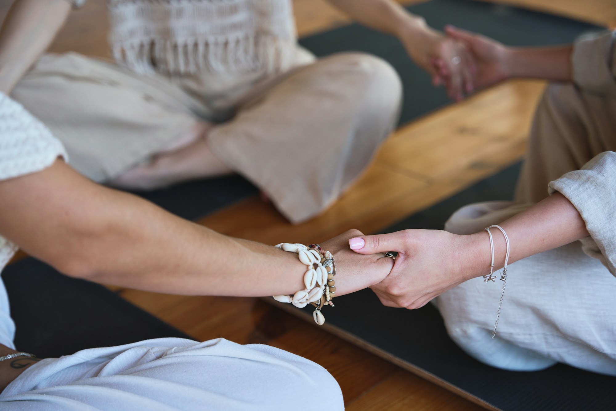 Yoga coach holding hands of women group during holistic healing session.